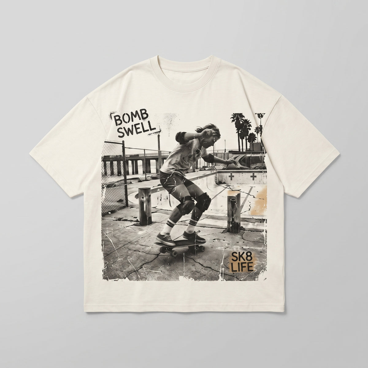 Camiseta oversize crema con estampado fotográfico de un skater en piscina vacía, texto Bomb Swell SK8 Life